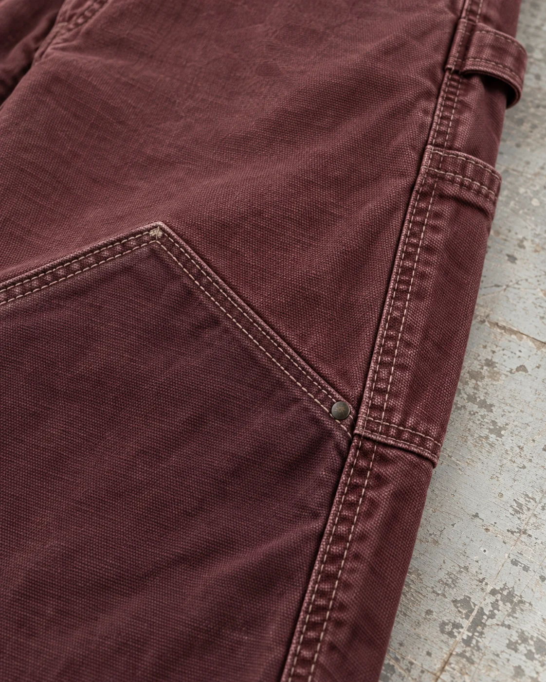 Close-up of fabric and signature construction — Canvas Carpenter Pants in faded oxblood / chalk, AI-generated design concept
