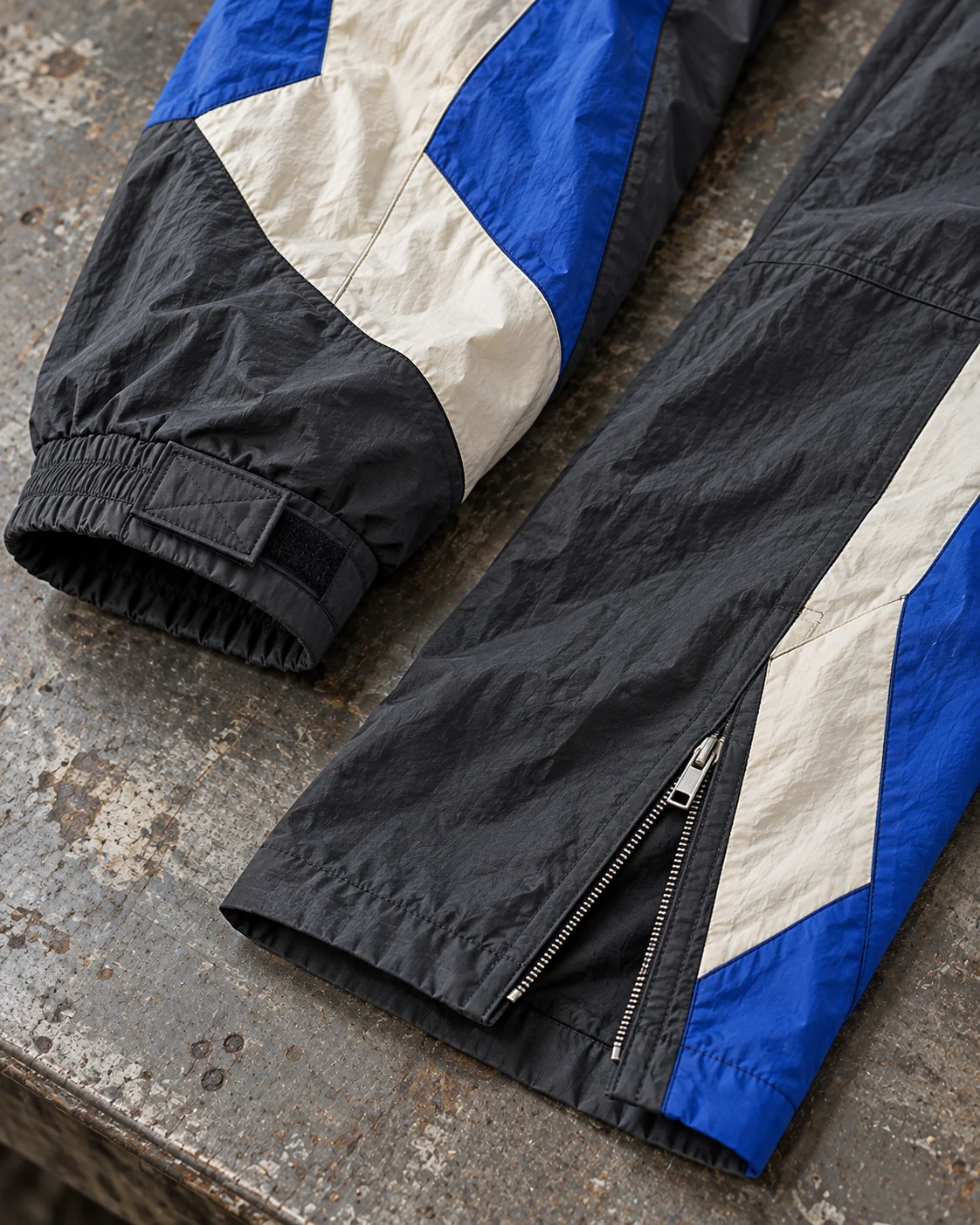 Close-up of fabric and coordinated construction — Color-Block Woven Tracksuit in charcoal / cobalt / bone, AI-generated design concept