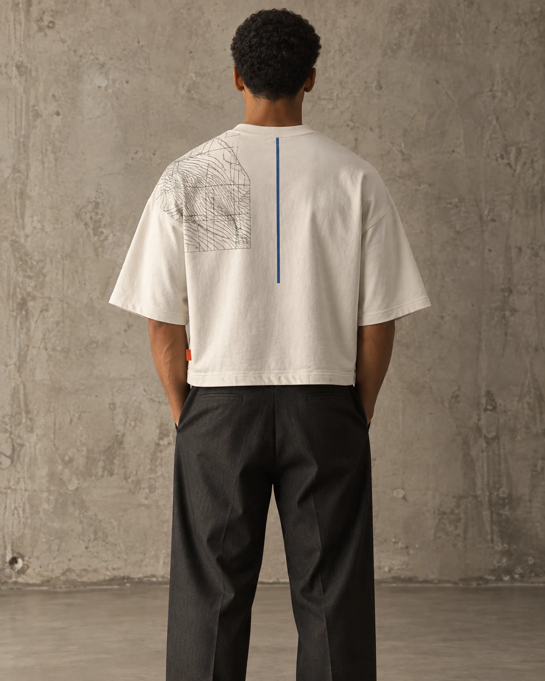 Back view of same model wearing cropped wide ivory T-shirt with asymmetric contour panel and narrow cobalt line