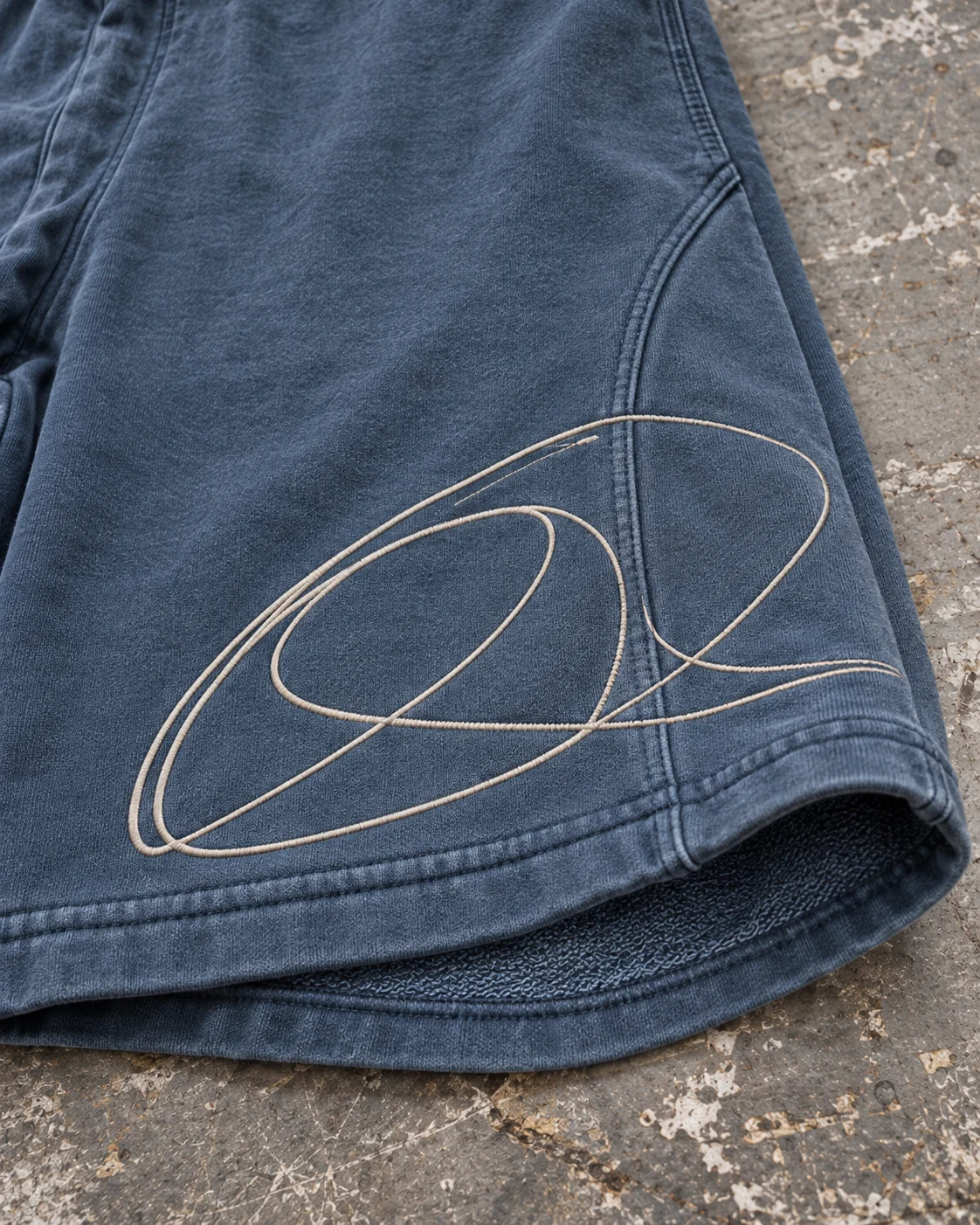 Close-up of fabric and signature construction — Heavyweight Sweat Shorts in faded petrol / cream, AI-generated design concept