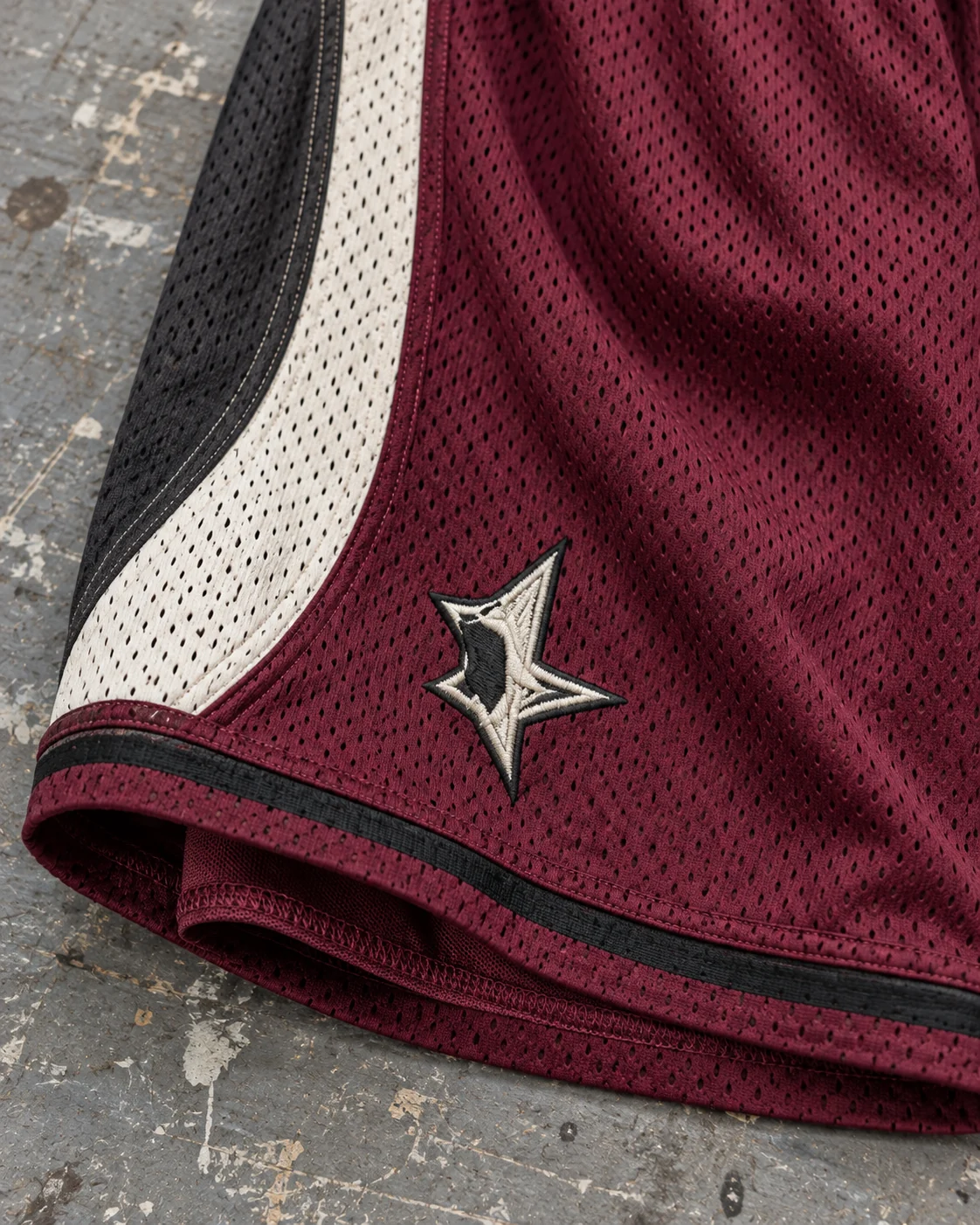 Close-up of fabric and signature construction — Mesh Basketball Shorts in burgundy / bone / charcoal, AI-generated design concept