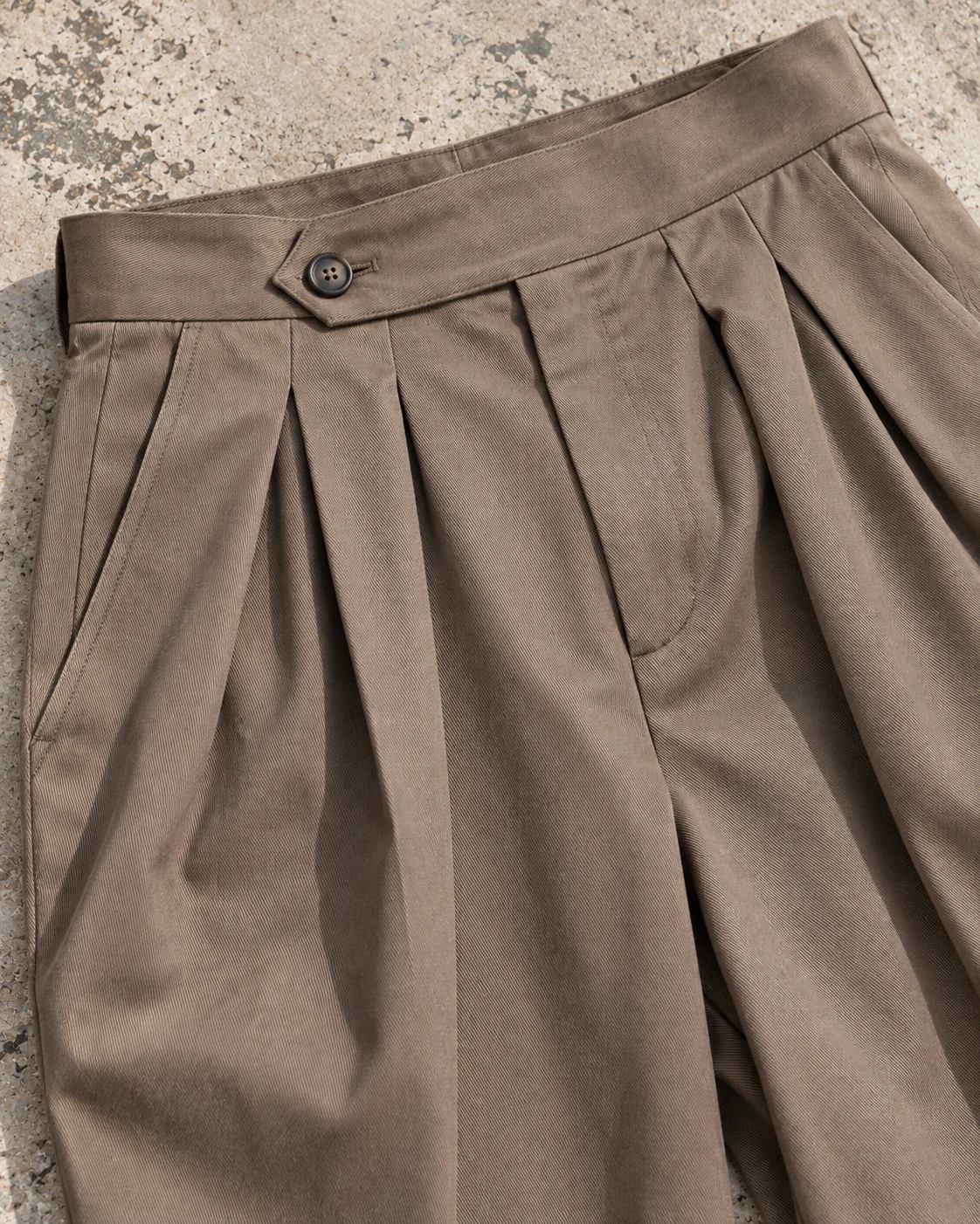 Close-up of fabric and signature construction — Pleated Wide-Leg Trousers in warm taupe / tonal, AI-generated design concept